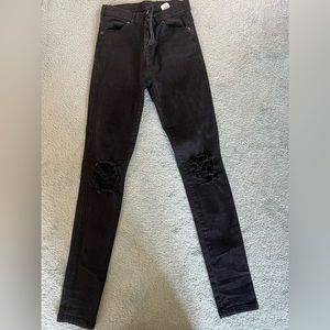 Black stretchy jeans with knee rips on each side.